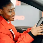 Mulher sentada ao volante de um carro avaliando o veículo antes da compra em uma concessionária na Irlanda.