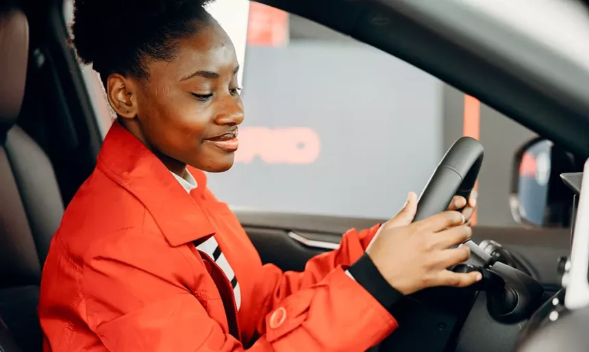 Mulher sentada ao volante de um carro avaliando o veículo antes da compra em uma concessionária na Irlanda.