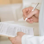Profissional de saúde preenchendo documentação médica para avaliação de benefício social.