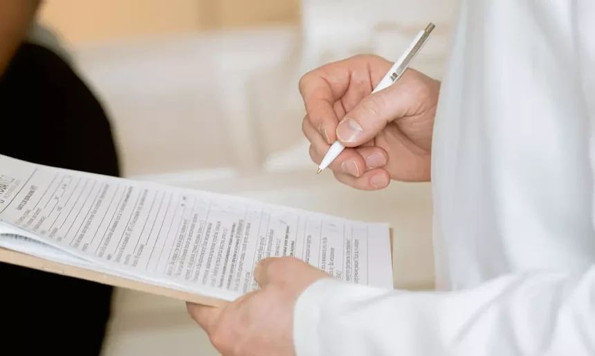 Profissional de saúde preenchendo documentação médica para avaliação de benefício social.