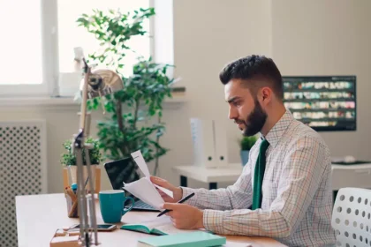 Homem analisando documentos e contas em um escritório doméstico.